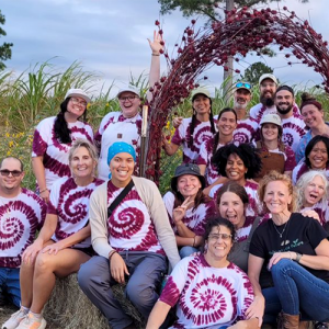 A group of people posing together, sitting on a haystack.